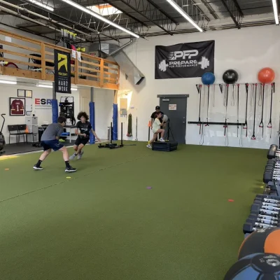 Children practicing soccer in an indoor gym with gym equipment and exercise balls on the wall